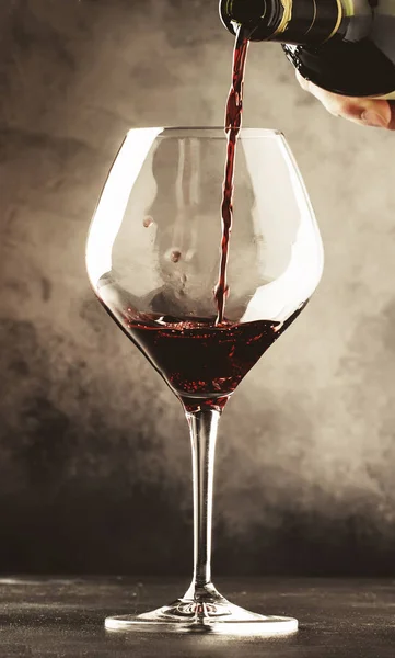 French dry red wine, pours into glass, gray background, selective focus