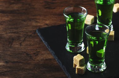 Absinthe-güçlü alkollü içecek, eski ahşap masada gözlük yeşil acı pelin tentür, metin için yer