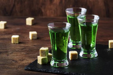 Absinthe-güçlü alkollü içecek, eski ahşap masada gözlük yeşil acı pelin tentür, metin için yer