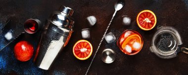 Trendy iç, Kuru cin, kırmızı vermut ve kırmızı acı, portakal dilimi ve buz küpleri ile alkollü kokteyl Negroni. Brown bar counter arka plan, araçlar, üstten görünüm, yaz ruh kavramı, kopya alanı bar