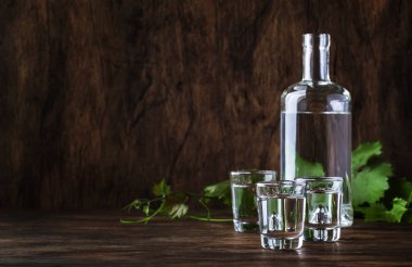 Aguardiente-geleneksel Ispanyol güçlü alkollü içecek, üzüm Moonshine veya votka, eski bir ahşap masada gözlük, metin için yer