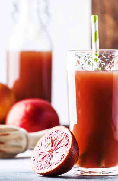 Summer juice or non-alcoholic refreshing healthy cocktail or drink from freshly squeezed red Sicilian orange, bright light table background. Selective focus