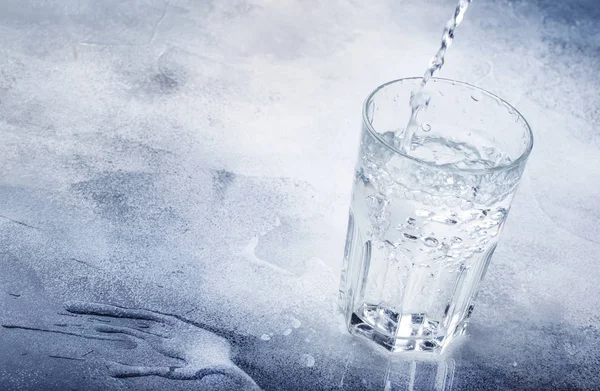 澄んだ水はガラス 灰色の背景 選択と集中にガラス瓶から注がれる — ストック写真
