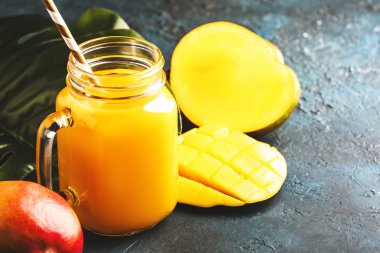 Mavi tropikal arka plan üzerinde taze meyve ile cam kavanozda Mango suyu veya kokteyl, kopya alanı, seçici odak