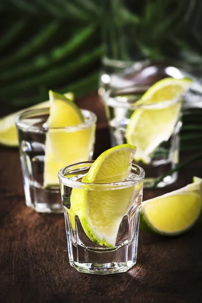 Cachaca - Brazilian strong alcoholic beverage from cane sugar, lime vodka, vintage wooden background, selective focus