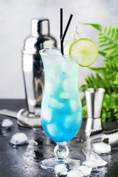 Blue Hawaiian or Blue Lagoon - summer alcoholic cocktail with vodka, liqueur, tonic, pineapple juice and ice, in high Hurricane glass, selective focus