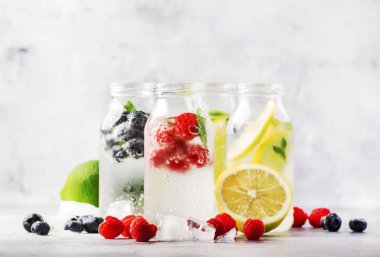 Yaz içkileri hazır. Berry, meyve ve narenciye alkolsüz serinletici buz soğuk içecekler ve kokteyller beyaz arka plan üzerinde cam şişeler