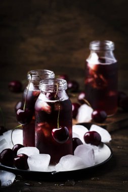 Kiraz içeceği, vintage ahşap masada şişelerde buz ile soğuk suyu, yaz meyve kokteyli