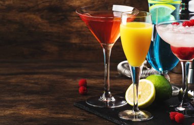 Yaz kokteyllerinden seçki. Soğuk serinletici alkollü içecekler ve içecekler: mimoza, kozmopolit, ahududu margarita ve mavi hawaii bar araçları ile ahşap bar sayacı