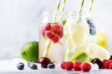 Yaz içkileri hazır. Berry, meyve ve narenciye alkolsüz serinletici buz soğuk içecekler ve kokteyller beyaz arka plan üzerinde cam şişeler