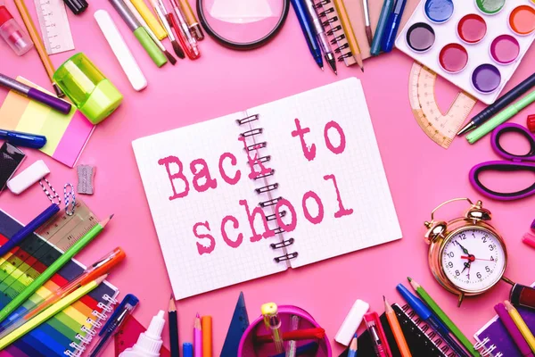 Back to school background with printed text, notebooks, pens, pencils, other stationery on pink modern background, education concept, flat lay, top view