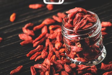 Goji meyveleri cam kavanoz, koyu ahşap masa, seçici odak