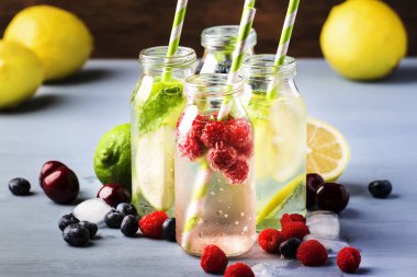 Berry, meyve ve narenciye alkolsüz soğuk içecekler ve mavi arka plan üzerinde cam şişelerde kokteyller, kopya alanı