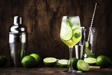 Beyaz vermut, prosecco, kireç, nane ve buz ile Martini royale alkollü kokteyl. Eski ahşap masa arka plan, bar araçları, seçici odak. Tüm isimler kokteyllere atıfta bulunur, ticari markalara değil