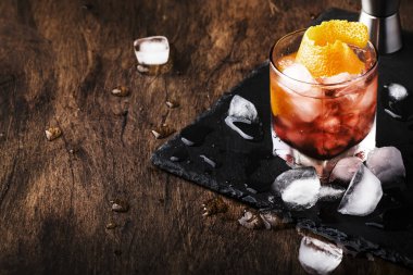 Kırmızı vermut ile Americano Alkol kokteyl, acı, soda, portakal lezzet ve buz, koyu ahşap bar sayacı arka plan, bar araçları, seçici odak