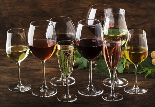 Wine tasting, still and sparkling wines. Red, white wine, rose and champagne  assortment in wine glasses on vintage wooden table background