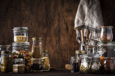 Tahıl stokları, makarna, Groats, organik baklagiller ve cam kavanozlarda kullanışlı tohumlar. Vejetaryen protein ve enerji kaynağı. Sağlıklı vejetaryen yemekleri. Ev hayatı sahnesi. Rustik ahşap mutfak masası arka planı. Seçici odak