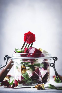 Pancar ve peynir sağlıklı salata arugula ve ceviz, trendy salata kavanozu, gri mutfak masası, metin için yer, seçici odak