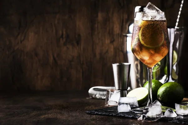 Alcoholic cocktail Long Island with vodka, gin, tequila silver, white rum, liqueur, sugar syrup, lemon juice, cola and ice cubes, vintage bar wooden counter background, selective focus