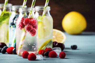 Berry, meyve ve narenciye alkolsüz soğuk içecekler ve mavi arka plan üzerinde cam şişelerde kokteyller, kopya alanı