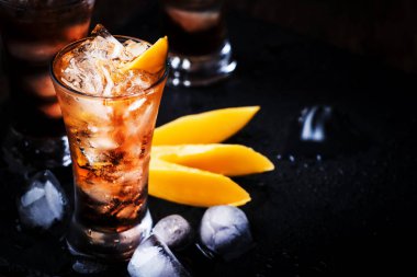 Mango ile alkollü kokteyl, kızılcık, kireç, ezilmiş buz ve likör, koyu ahşap bar sayacı arka plan, seçici odak