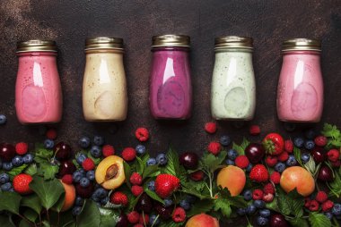 Renkli berry cokctalis, smoothies ve taze meyve ve çilek kahverengi mutfak masa arka plan, düz yatıyordu, üst görünümü ile milkshakes