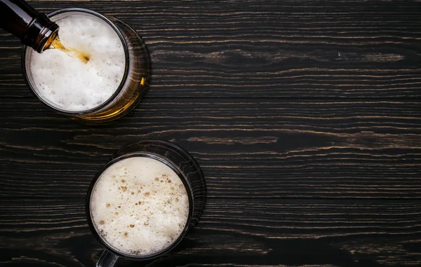 Dark beer, ale or stout is poured into glass, dark wooden bar counter, space for text, top view