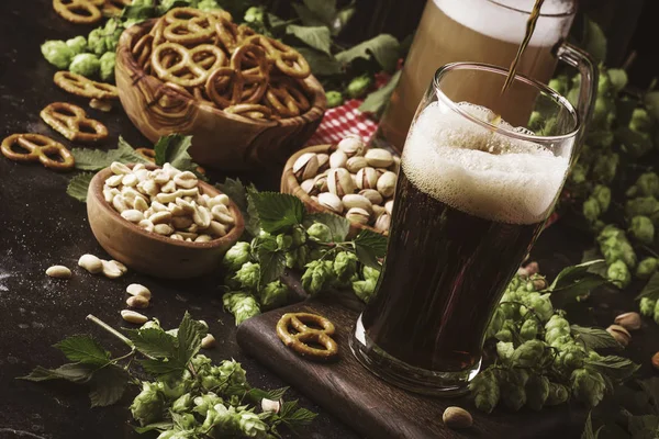 Dark english beer, ale or stout is poured into glass, dark bar counter, space for text, selective focus