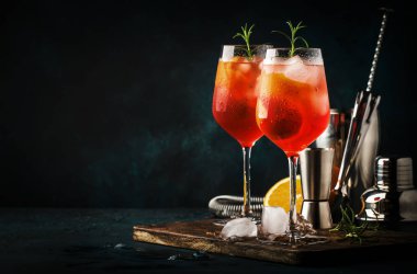 Kırmızı acı, kuru beyaz şarap, soda, lezzet ve buz ile Milano spritzer alkollü kokteyl. Koyu mavi arka plan, bar araçları, seçici odak
