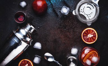 Kuru cin, kırmızı vermut ve kırmızı acı, kanlı portakal dilimi ve buz küpleri ile Negroni alkollü kokteyl içecek. Kahverengi bar sayacı arka plan, çelik çubuk araçları, üst görünüm, kopyalama alanı ile