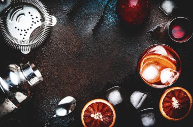 Kuru cin, kırmızı vermut ve kırmızı acı, kanlı portakal dilimi ve buz küpleri ile Negroni alkollü kokteyl içecek. Kahverengi bar sayacı arka plan, çelik çubuk araçları, üst görünüm, kopyalama alanı ile
