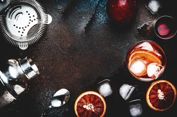 Kuru cin, kırmızı vermut ve kırmızı acı, kanlı portakal dilimi ve buz küpleri ile Negroni alkollü kokteyl içecek. Kahverengi bar sayacı arka plan, çelik çubuk araçları, üst görünüm, kopyalama alanı ile
