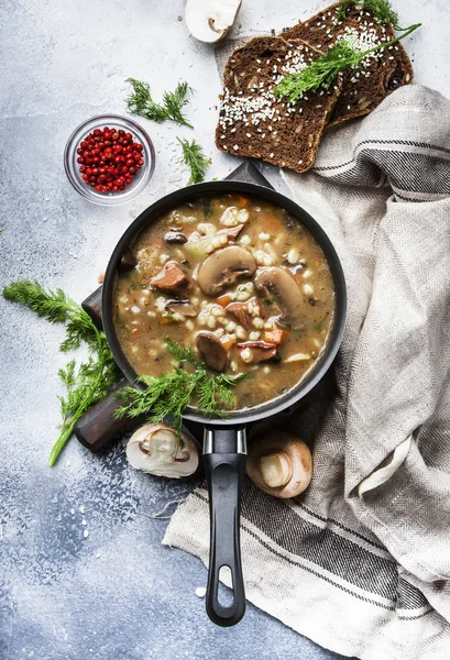 Autumn or winter meat vegetable mushroom hot soup with beef and wholegrain barley. With black brea and parsley, top view, gray kitchen table, copy space — Stock Image Autumn Winter Meat Vegetable Mushroom Hot Soup Beef Wholegrain Barley Stock Photo