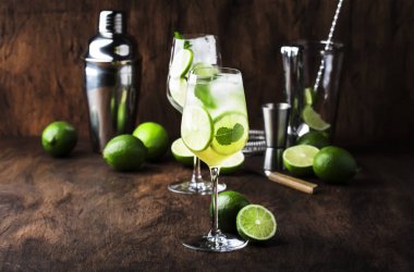 Beyaz vermut, prosecco, kireç, nane ve buz ile Martini royale alkollü kokteyl. Eski ahşap masa arka plan, bar araçları, seçici odak. Tüm isimler kokteyllere atıfta bulunur, ticari markalara değil