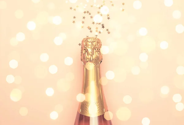Christmas or New Year pink background with  bottle of sparkling wine, rose champagne and gold decor, top view