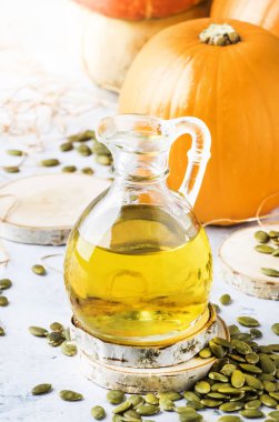 Beyaz rustik arka plan üzerinde cam sürahi kabak çekirdeği yağı, kopya alanı, seçici odak