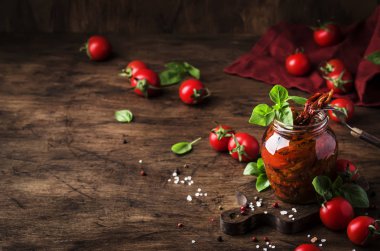 İtalyan Güneşi Kurutulmuş domates zeytinyağında yeşil fesleğen ve baharatlar ile cam kavanozda ahşap mutfak masası, rustik tarzı, kopya alanı