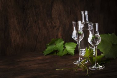 Grape vodka, pisco - traditional Peruvian strong alcoholic drink in elegant glasses on vintage wooden table, copy space clipart