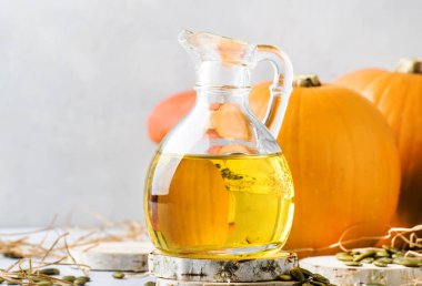 Beyaz rustik arka plan üzerinde cam sürahi kabak çekirdeği yağı, kopya alanı, seçici odak