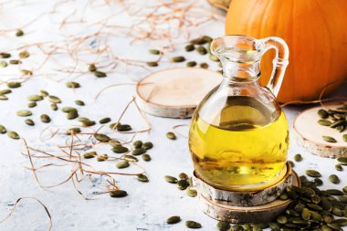 Beyaz rustik arka plan üzerinde cam sürahi kabak çekirdeği yağı, kopya alanı, seçici odak