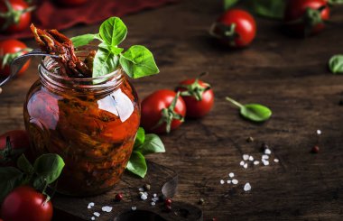 İtalyan Güneşi Kurutulmuş domates zeytinyağında yeşil fesleğen ve baharatlar ile cam kavanozda ahşap mutfak masası, rustik tarzı, kopya alanı