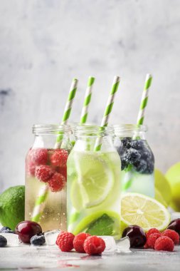 Berry ve narenciye alkolsüz içecekler ve gri taş masa arka plan üzerinde cam şişelerde kokteyller, kopya alanı