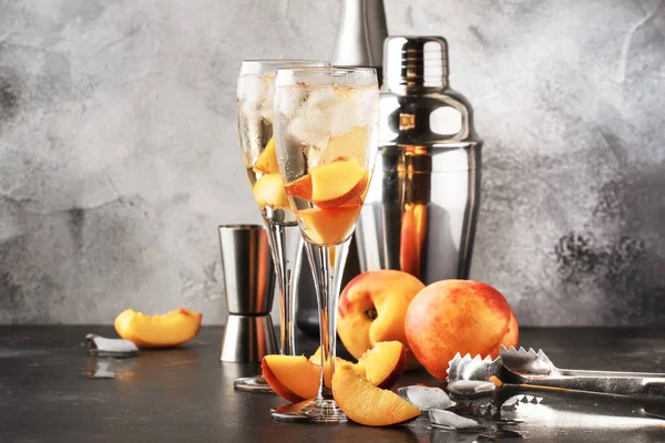 Bellini, alcoholic cocktail with sparkling wine, sugar syrup, lemon juice, peach and ice, gray table background, copy space