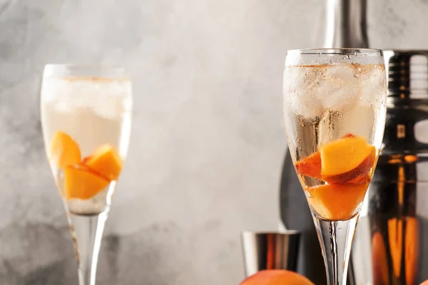 ベリーニ スパークリングワイン 砂糖シロップ レモンジュース 桃と氷 灰色のテーブルの背景 コピースペースとアルコールカクテル — ストック写真