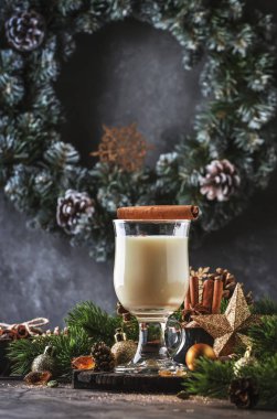 Yeni Yıl veya Noel Eggnog kokteyl - sıcak kış veya süt, yumurta ve koyu rom ile sonbahar içki, tarçın ve hindistan cevizi ile ahşap arka plan, şenlikli dekorasyon bir bardak serpilir