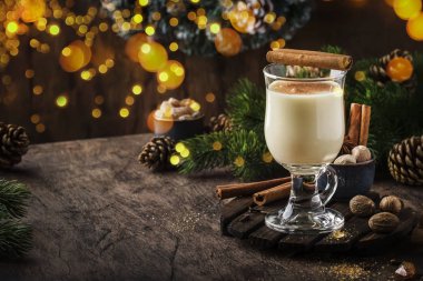 Yeni Yıl veya Noel Eggnog kokteyl - sıcak kış veya süt, yumurta ve koyu rom ile sonbahar içki, tarçın ve hindistan cevizi ile ahşap arka plan, şenlikli dekorasyon bir bardak serpilir