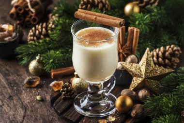 Yeni Yıl veya Noel Eggnog kokteyl - sıcak kış veya süt, yumurta ve koyu rom ile sonbahar içki, tarçın ve hindistan cevizi ile ahşap arka plan, şenlikli dekorasyon bir bardak serpilir