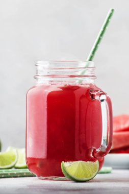 Cam kavanozda kireç ve gri mutfak masası arka planda karpuz dilimleri ile taze sıkılmış karpuz smoothie