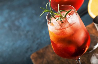 Kırmızı acı, kuru beyaz şarap, soda, lezzet ve buz ile Milano spritzer alkollü kokteyl. Koyu mavi arka plan, bar araçları, seçici odak