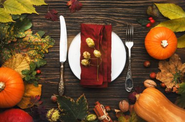 Şükran Günü yemeği. Sonbahar meyvesi, balkabağı, fındık, tabak ve çatal bıçaklı yapraklar. Şükran Günü sonbahar arkaplanı